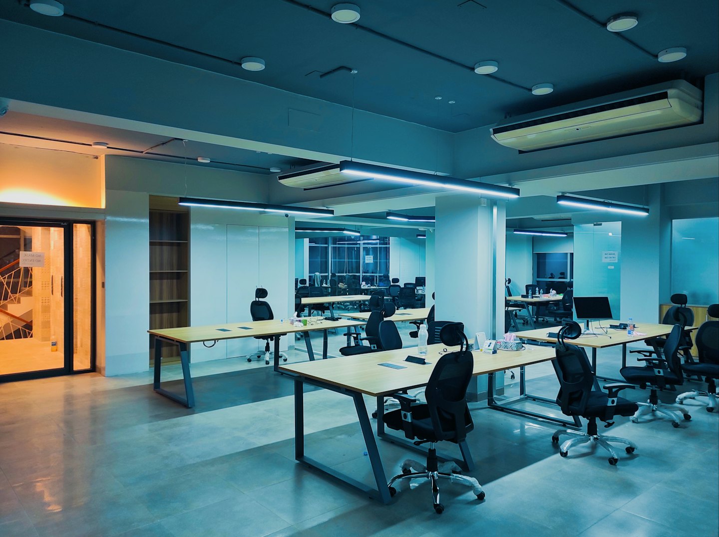 Modern open-plan office with wooden desks and computer monitors.